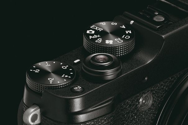Die X10 orientiert sich an Analogkameras und bietet klassische Belichtungsprogramme und Bedienelemente wie das EV-Belichtungskorrekturrad (links im Bild) oder den Auslöser mit praktischem Gewinde für einen Drahtkabelauslöser (Bildmitte).