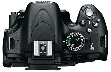 Die Top-Ansicht der Nikon D5100 zeigt das Modusrad und an diesem der zurück schnellende Live-View-Schalter (LV). Weiter sind die zwei Auslöser für Foto (chrom) und Video (rot) sowie die Info-Taste und die Plus-Minus-Korrektur zu sehen. Über letztere wird im manuellen Modus die Blende verstellt.