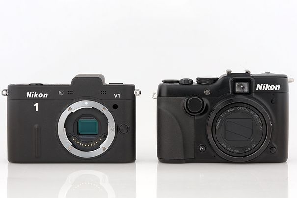 Kompakte Konkurrenz: Die Nikon 1 V1 ist als Vertreterin der kompakten spiegellosen Systemkameras im Vergleich zur Kompaktkamera Coolpix P7100 etwas kleiner. Mit montiertem Objektiv ist die V1 sperriger, während die P7100 ihr Objetiv einziehen kann.