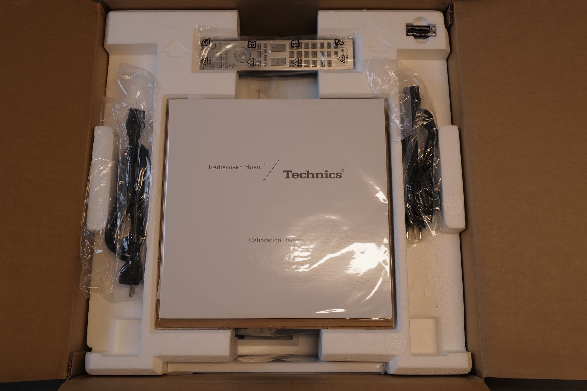 Unboxing: Nach dem Öffnen blickt man überrascht/gespannt auf eine Vinyl-Schallplatte für Einmess-Zwecke.