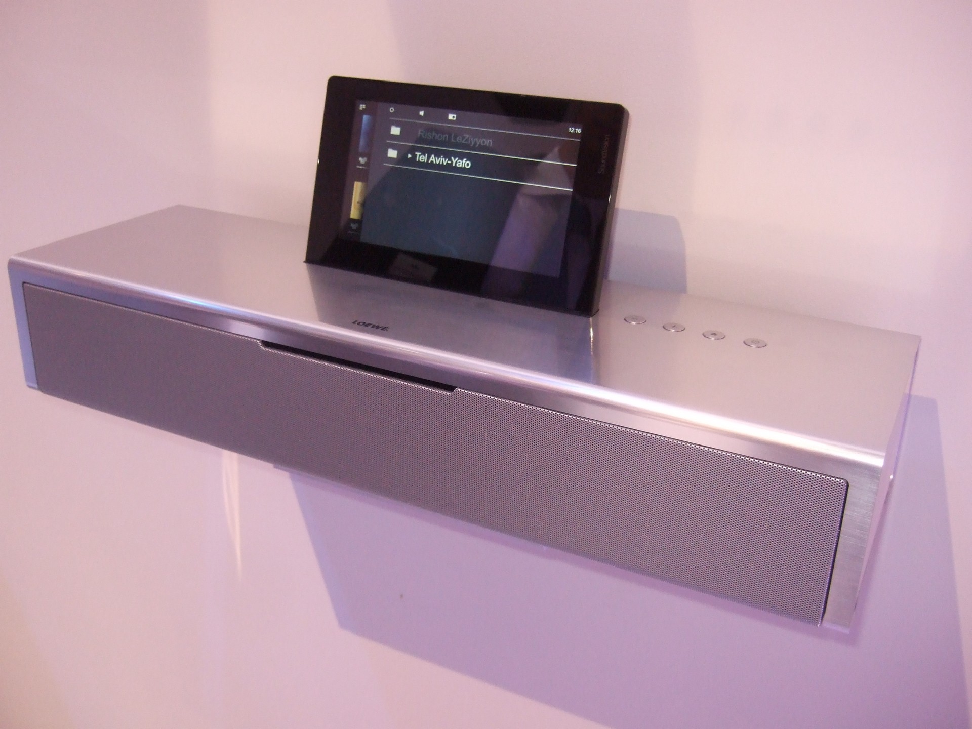 SoundVision, so heisst die neue, multifunktionale Dockingstation des deutschen Herstellers Loewe. FM- und Internetradio, LAN, WLAN, Powerline, eine Schnittestelle für den iPad und sogar einen integrierten CD-Player hat SoundVision an Bord. Die Bedienung erfolgt über ein 7,5 Zoll Multi Touch Display oder per Fernbedienung Loewe Assist.