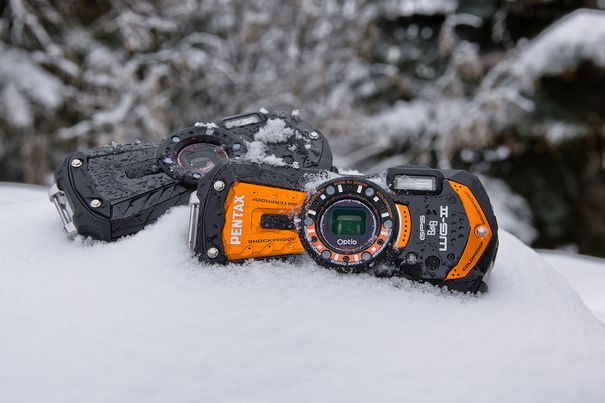 Wasserdichte Kameras wie die Pentax Optio WG2 (hinten) und WG2-GP (vorne) fühlen sich ebenso wohl in Schnee und Eis, wie im und am Wasser eines tropischen oder mediterranen Sandstrands.