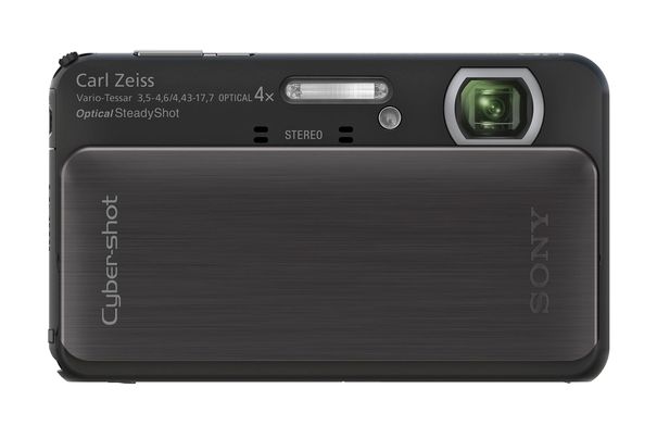 Die Sony TX20 mit herunter geschobener Frontabdeckung trumpft mit flachem Metallgehäuse auf. Links oben in der Ecke steht der Zoomhebel hervor, während sich weiter zur Mitte der Auslöser erhebt und daneben der Einschalter gerade noch zu sehen ist.